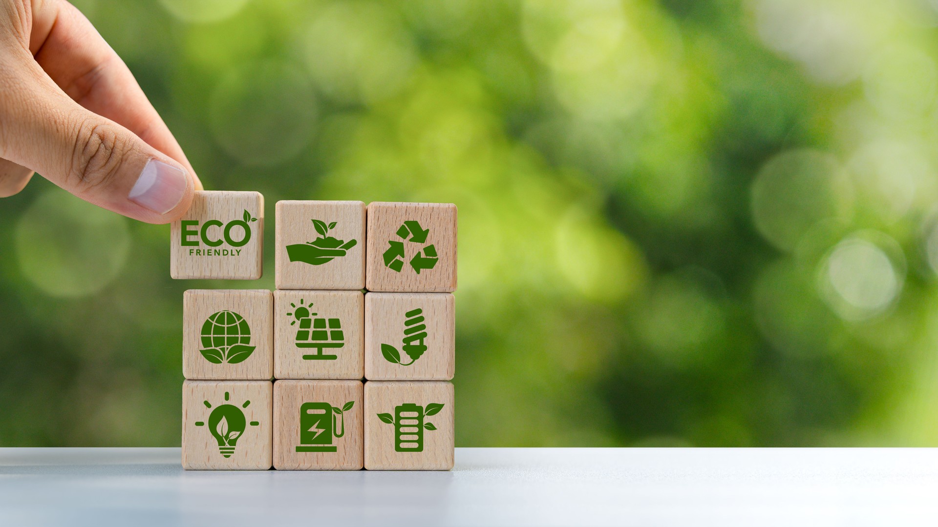 Concetto di economia circolare ECO, riciclaggio, ambiente, riutilizzo, produzione, rifiuti, consumatore, risorse, valutazione del ciclo di vita, LCA, sostenibilità. Mano che tiene un blocco di legno con icona verde. Spazio di copia